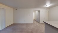 Located at 2403 Toledo Rd in Elkhart, Indiana, this single-floor residential unit offers a practical and well-organized layout designed for comfortable everyday living. The galley-style kitchen is efficiently arranged with rich warm-toned wood cabinetry lining both sides, light countertops, tile flooring, and white appliances including a refrigerator and stove, providing ample storage and workspace. A doorway at the end of the kitchen connects conveniently to additional areas of the unit. The open living area features neutral carpeting and clean white walls, creating a bright and versatile space with a clear sightline toward the hallway and closet storage beyond. The bedroom is a well-proportioned, carpeted room bathed in natural light from a window fitted with blinds, offering a calm and restful atmosphere. The full bathroom is cleanly finished with tile flooring, a warm wood-toned vanity with a white countertop, a wall mirror with an illuminated fixture above, and a full bathtub and shower combination. Throughout the unit, the design emphasizes clean lines, neutral tones, and functional finishes, making it a straightforward and move-in ready space.