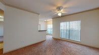 Located at 1301 Latta St in Midland, Texas, this single-floor unit offers a well-organized layout designed for comfortable everyday living. The open living area is finished with warm neutral carpet and features crown molding along the ceiling, a ceiling fan with light fixture, and large windows fitted with vertical blinds that allow ample natural light to fill the space. A half-wall pass-through connects the living area to the adjacent dining or kitchen zone, adding an open, connected feel throughout.

The galley-style kitchen is efficiently laid out with honey-toned wood cabinetry lining both sides, dark laminate countertops, a double-basin sink, and a full suite of black appliances including a refrigerator, electric range, and built-in microwave. The kitchen features a classic checkered vinyl floor and leads directly to a closet for added storage.

The bedrooms are carpeted and include ceiling fans, neutral walls, and windows that bring in natural light. Crown molding details are present in select rooms, adding a refined touch. The bathrooms are finished with tile flooring and feature full soaking tubs with tiled surrounds accented by a decorative brown tile border, paired with wood-toned vanities and granite-look countertops. The overall aesthetic is clean, functional, and well-maintained throughout.