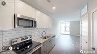 Located at 614 Rigsbee Ave in Durham, NC, this one-bedroom, one-bathroom unit offers a thoughtfully designed layout with modern finishes throughout. Light-toned hardwood-style flooring flows consistently across the entire space, complementing the neutral warm-gray walls and crisp white trim that give the unit a clean, contemporary aesthetic.

The combined kitchen and living area serves as the heart of the unit. The kitchen is equipped with stainless steel appliances, including a full-size refrigerator, electric range, and built-in microwave. Granite countertops, two-tone cabinetry in white and gray, and a horizontal subway tile backsplash contribute to the modern design. The open layout allows the kitchen to connect naturally to the living area.

The bedroom is a comfortable, well-proportioned space featuring a ceiling fan with light fixture and a large floor-to-ceiling window that brings in ample natural light and views of the surrounding urban neighborhood. A dedicated walk-in closet provides practical storage directly off the bedroom.

The bathroom features a walk-in shower with floor-to-ceiling white tile and a black-framed glass door, a granite-topped vanity with an undermount sink, a framed mirror, and wood-style flooring that ties the space together cohesively. The unit's overall design reflects a polished, modern sensibility well-suited to urban living in downtown Durham.