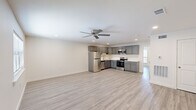This single-story unit in Houma, Louisiana, presents a clean, modern aesthetic carried consistently throughout its layout. Light-toned luxury vinyl plank flooring runs through every room, complementing the crisp white walls and creating a bright, cohesive interior. Ceiling fans are installed in the main living areas and bedroom, providing both comfort and airflow.

The open-concept living and kitchen area forms the heart of the unit. The kitchen is well-equipped with gray shaker-style cabinetry offering generous storage, light-colored countertops, a stainless steel refrigerator, electric range, over-the-range microwave, and dishwasher. Recessed lighting illuminates the space efficiently.

The bedroom is a comfortable, well-proportioned room featuring a ceiling fan with light fixture, a window with blinds that allows natural light, and closet access. Additional rooms include utility-oriented spaces with visible HVAC vents and an electrical panel, ensuring practical functionality.

The bathroom is neatly finished with a gray vanity cabinet, white countertop, wall-mounted mirror, and a tub-shower combination, maintaining the consistent modern style found throughout the unit.