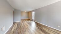 Located at 2765 Coldstream Lane in Columbus, Ohio, this single-floor, one-bedroom, one-bathroom home offers a practical and well-organized layout finished with clean, neutral tones throughout. The living room is a bright, open space featuring warm wood-look laminate flooring, gray painted walls, crisp white baseboards, and a textured ceiling. Multiple windows allow natural light to fill the room, creating an airy and welcoming atmosphere, while a front entry door provides direct access to the exterior. The space flows efficiently into the rest of the home, reflecting a straightforward single-level floor plan visible in the overhead model view. The bedroom is a generously sized retreat finished with plush wall-to-wall carpeting and gray walls. Two large windows fitted with blinds invite natural light while maintaining privacy. A standout feature of the bedroom is the expansive dual sliding-door closet system spanning the full width of one wall, providing substantial and well-organized storage. The bathroom is clean and functional, finished with tile flooring and featuring a full-sized soaking tub with an overhead shower, a curved shower rod, a toilet, and a towel bar — all in a bright white and gray palette. Overall, this home presents a tidy, move-in-ready aesthetic with consistent finishes throughout.