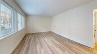 Located at 295 3rd St in Lake Oswego, Oregon, this 2-bedroom, 1-bathroom unit offers a well-organized, single-level layout. Light hardwood flooring runs throughout, creating a cohesive and clean aesthetic across every room. The open living area is filled with natural light from a row of large windows overlooking the streetscape, lending a bright and airy feel to the space. The kitchen flows directly from the living area and features white shaker cabinetry, dark countertops, stainless steel appliances including a freestanding range, and a window that brings in additional natural light. A hallway connects the main living areas to the two bedrooms, each of which includes a ceiling fan with light fixture, a closet, and a window with outdoor views of surrounding greenery. The primary bedroom offers a comfortable footprint with access to its own closet. The full bathroom is finished with white subway tile surround on the tub-shower combination, chrome fixtures, and a frosted privacy window. Three closets throughout the unit provide ample storage. The unit's clean, neutral palette and updated finishes create a functional and inviting living environment in the heart of Lake Oswego.