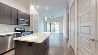 Located at 3964 Watercourse Dr in Fort Worth, TX, this well-appointed one-bedroom, one-bathroom residence offers a thoughtfully designed layout with modern finishes throughout. Wood-style flooring flows seamlessly across the entire unit, lending warmth and visual continuity to every room.

The kitchen is a standout feature, showcasing rich dark cabinetry that extends to the ceiling, a light green glass tile backsplash, gleaming white quartz countertops, and a full suite of stainless steel appliances including a refrigerator with ice maker, range, microwave, and dishwasher. A farmhouse-style sink adds a refined touch, while a central island with built-in outlets provides additional prep space and casual seating.

The kitchen opens directly to the living area, which is bathed in natural light from a large sliding glass door leading to a private balcony. A ceiling fan overhead enhances comfort in the combined living space.

The bedroom is a quiet, well-proportioned retreat with clean white walls and access to a generously sized walk-in closet outfitted with double hanging rods and shelving. The bathroom features a soaking tub with a tiled surround and wood-look flooring, maintaining the cohesive aesthetic found throughout the unit.