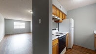 Located at 905 N Newton Ave in El Dorado, Arkansas, this single-story home offers a practical and functional layout throughout. The interior is finished with cool gray tones on the walls and textured ceilings, creating a consistent and neutral aesthetic across all rooms.

The open living area is a highlight of the home, featuring rich, dark wood-look vinyl plank flooring that extends throughout the main living spaces. Natural light filters in through windows, enhancing the spacious feel of the room. The living area connects directly to the galley-style kitchen, which is equipped with warm honey-toned wood cabinetry, white countertops, a coil-burner electric range, a full-size refrigerator, a dishwasher, and an under-cabinet range hood. The kitchen also includes a double sink and ample upper and lower cabinet storage.

The bedrooms are carpeted in a neutral tone and share the same cool gray wall color. Each room includes windows with blinds that allow for natural light and privacy. At least one bedroom features a walk-in closet with a closet rod for storage. The bathroom includes a full-size tub and shower combination with a white surround, a wood-vanity with storage below, and wood-look vinyl plank flooring consistent with the rest of the home.