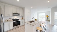 Located at 3025 Woodward Crossing Blvd in Buford, GA, this well-appointed one-bedroom, one-bathroom residence offers a thoughtfully designed open-concept floor plan finished with contemporary details throughout. Light-toned luxury vinyl plank flooring flows through the main living areas, complemented by crisp white walls and recessed lighting that create a bright, airy atmosphere.

The kitchen serves as the heart of the home, showcasing white shaker cabinetry, a herringbone tile backsplash, granite countertops, and a full suite of stainless steel appliances including a range, over-the-range microwave, and French door refrigerator. A central island with a granite top and undermount sink provides additional prep space and casual bar seating, opening seamlessly into the living area.

The living room extends toward a sliding glass door that leads to a private balcony, offering outdoor views and natural light. The bedroom is carpeted for comfort, features a ceiling fan, and is illuminated by a large window with outdoor views.

The bathroom is generously sized, presenting a dual-sink granite vanity with chrome fixtures, a large mirror with contemporary lighting, and clean white finishes. A dedicated in-unit laundry room with full-size washer and dryer adds everyday convenience to this well-rounded residence.