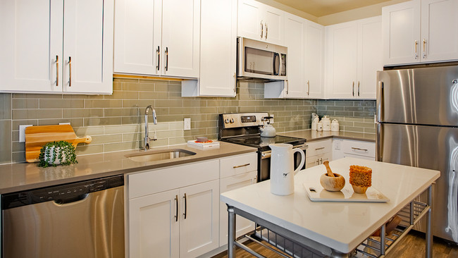 Kitchen featuring modern white cabinetry, stainless steel appliances and movable island - Modera 55