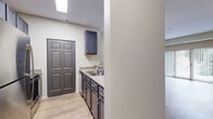 This 1-bedroom, 1-bathroom residence in Burnsville, Minnesota offers a practical and well-designed layout across a single floor. The welcoming entrance leads into a bright living room featuring light wood-look flooring, neutral wall tones, and a sliding glass door that opens onto a private patio with outdoor views of mature trees, allowing natural light to fill the space.

The kitchen is a standout feature, showcasing slate-gray cabinetry with modern hardware, a subway tile backsplash, stainless steel appliances including a refrigerator, microwave, and range, and a peninsula with countertop seating. A skylight above and under-cabinet lighting enhance the kitchen's functionality and style. An adjacent pantry provides additional storage.

The bedroom is generously sized with plush wall-to-wall carpeting, a large window with outdoor views, and access to a walk-in closet, offering ample storage. The full bathroom is clean and functional, featuring a full-size soaking tub and surround.

Additional practical amenities include a dedicated laundry area, a utility room, and two closets throughout the unit. Light wood-look flooring runs through the main living areas, complementing the neutral color palette maintained throughout the home. The overall ambiance is clean, modern, and move-in ready.