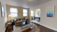 Located at 236 W Walnut Lane in Philadelphia, PA, this single-floor residence combines classic architectural character with a clean, functional layout. The living room serves as the heart of the space, showcasing rich, polished hardwood floors that add warmth and depth to the interior. Multiple windows fitted with blinds allow generous natural light to fill the room, creating a bright and welcoming atmosphere. Crown molding along the ceiling adds a refined architectural touch, while a cast-iron radiator reflects the home's period charm. A graceful arched doorway connects the living room to the adjacent dining area, providing an elegant sense of separation while maintaining an open, flowing feel. The dining area transitions to lighter tile flooring and benefits from its own window, ensuring continued natural illumination. Neutral wall tones throughout the home provide a versatile backdrop, complementing both the living and dining spaces. The overall ambiance is one of understated elegance, blending original architectural details with a clean, approachable aesthetic well-suited for comfortable everyday living in a classic Philadelphia setting.