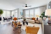 This well-appointed single-floor residence showcases a thoughtfully designed open-concept layout that seamlessly connects the kitchen, living, and dining areas. The kitchen is a standout feature, boasting white shaker cabinetry, a subway tile backsplash, stainless steel appliances, and a large central island with granite countertops, a undermount sink, and pendant lighting — ideal for both meal preparation and casual dining. The open living area is bathed in natural light from an expansive array of large windows dressed with elegant striped drapes, offering views of the outdoors. A ceiling fan adds a practical touch to this generous gathering space. The adjacent dining area is equally light-filled, with floor-to-ceiling windows on multiple walls creating a bright, airy atmosphere. The bedroom is a serene retreat featuring plush carpeting, a ceiling fan, and a walk-in closet equipped with wire shelving systems for organized storage. The bathroom includes a tub-shower combination with classic white subway tile surround, granite vanity countertop, and hardwood-style flooring. Rich dark hardwood-style floors run throughout the main living areas, tying together the cohesive, contemporary aesthetic of this inviting residence.