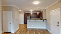 Located at 507 Carowill Dr in Greensboro, NC, this single-story residence offers a thoughtfully designed interior with a cohesive blend of modern finishes throughout. The open-concept living and kitchen area serves as the heart of the home, anchored by rich, dark espresso cabinetry that extends to the ceiling for ample storage. Granite countertops with subtle veining run throughout, complementing a full suite of stainless steel appliances, including a refrigerator, electric range, and built-in microwave. A peninsula with bar-top seating and pendant lighting overhead adds both functionality and style, while wood-look plank flooring grounds the space with warmth. Crown molding adds a refined architectural detail throughout the main living areas. The bedrooms are finished with plush carpeting and feature windows with blinds that allow natural light to filter in; one bedroom includes a ceiling fan. Each bathroom is well-appointed, featuring tub and shower combinations, granite-topped vanities with dark cabinetry, wood-look flooring, and convenient closet storage with wire shelving systems. The overall ambiance is clean, contemporary, and practical.