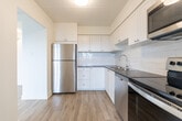 Located at 110 Nonquon Rd in Oshawa, Ontario, this clean and well-appointed 2-bedroom, 1-bathroom unit offers a thoughtfully designed single-floor layout. Light-toned hardwood flooring runs throughout, lending warmth and continuity to the space.

The open living room is a standout feature, bathed in natural light from large sliding glass doors that lead to a private balcony with outdoor views of mature trees. A second window further brightens the room, creating an airy, welcoming atmosphere. Baseboard heating is present throughout for year-round comfort.

The kitchen is efficiently laid out with white cabinetry, a subway tile backsplash, stainless steel appliances including a refrigerator and range with overhead microwave, and a stainless steel sink — offering both style and functionality.

Both bedrooms are comfortably sized and filled with natural light from large windows framing green outdoor views. The primary bedroom features a sliding-door closet for ample storage, while both rooms benefit from wall-mounted lighting fixtures. A hallway connects the bedrooms to the shared full bathroom, which is finished with classic white subway tile surrounding a full bathtub and shower combination with chrome fixtures.

The layout flows intuitively from the living and kitchen areas through a central hallway to the private bedrooms, making efficient use of the available space.