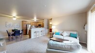 This single-floor residence offers a thoughtfully designed open-concept layout that seamlessly connects the living area and kitchen. The living room features plush carpeting, neutral-toned walls, and a sliding glass door that invites natural light and provides access to an outdoor area. The kitchen is well-equipped with stainless steel appliances — including a refrigerator, range, and microwave — complemented by warm wood cabinetry, granite-style countertops, and wood-look flooring. A breakfast bar with seating adds functionality to the space.

The primary bedroom is generously sized with carpeted floors, a ceiling fan, and a window that allows natural light to fill the room. A second bedroom also features carpet, a closet with sliding doors, and a window overlooking the exterior. Both bathrooms are finished with rich wood vanities, granite-style countertops, and wood-look flooring. One bathroom includes a walk-in shower, while the other offers additional cabinet storage.

A dedicated laundry room houses a full-sized washer and dryer alongside a water heater, adding everyday convenience. Throughout the residence, the warm, neutral color palette and consistent finishes create a cohesive and comfortable living environment.