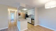 This single-floor residence offers a thoughtfully designed open-concept layout that seamlessly connects the living area to the kitchen. The kitchen is a functional highlight, featuring crisp white shaker-style cabinetry, granite countertops, a subway tile backsplash, and a full suite of stainless steel appliances including a refrigerator, dishwasher, range, and microwave. A peninsula with a granite surface provides additional prep space and serves as a natural divider between the kitchen and the open living area. Light wood-look flooring runs throughout the main living areas, lending a clean and cohesive aesthetic.

The living room is bright and airy, with a sliding glass door that opens to an outdoor balcony, allowing natural light to flow into the space. The bedrooms are carpeted for comfort and each feature windows that bring in natural light and outdoor views. The bathroom is cleanly finished with a white vanity topped with granite, a full soaking tub with shower, and matching wood-look flooring. Textured ceilings are present throughout, and neutral wall tones create a versatile backdrop. Overall, the space presents a modern, move-in-ready feel with consistent finishes across every room.