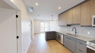 Located on the 8th floor at 909 Fifth Ave SW in downtown Calgary, this modern 2-bedroom, 1-bathroom unit offers a thoughtfully designed open-concept layout across a single floor. Light hardwood flooring flows throughout the entire space, creating a warm and cohesive aesthetic.

The kitchen is a standout feature, showcasing two-tone cabinetry with warm wood uppers and slate-grey lowers, light quartz countertops, a white penny-tile backsplash, and a peninsula island with an undermount sink and matte black faucet. Stainless steel appliances — including a refrigerator, electric range, built-in microwave, and dishwasher — complete the space. A sleek linear pendant light fixture anchors the kitchen visually. Recessed lighting and a window bring in natural light, connecting seamlessly to the open living area.

The primary bedroom is a cozy and functional retreat, while the second bedroom features a large window framing city views and a sliding mirrored closet door that adds depth and reflects natural light. Both rooms are finished with clean white walls and consistent hardwood flooring. The overall ambiance of the unit is clean, contemporary, and move-in ready, ideal for urban living in the heart of Calgary.