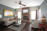 This thoughtfully designed single-floor residence offers a comfortable and cohesive living experience across multiple well-defined spaces. The living room serves as the heart of the home, showcasing rich hardwood flooring, a striking corner brick fireplace with a wood mantle, and a ceiling fan overhead. A teal accent wall adds a bold splash of color, complemented by natural light filtering through multiple windows with blinds and decorative curtains.

The kitchen is both functional and open, featuring white cabinetry, dark countertops, a full suite of appliances, and a breakfast bar that connects seamlessly to the main living areas. Adjacent to the kitchen, the dining area is anchored by a dark wood table set beneath a classic chandelier, with a rich chocolate-brown accent wall adding warmth and depth.

The primary bedroom offers plush carpeting, a ceiling fan, and access to a spacious en-suite bathroom complete with a corner jetted soaking tub, a separate walk-in shower, and a large vanity mirror. A second bedroom provides equally comfortable carpeted accommodations with its own ceiling fan and natural light. A second full bathroom includes a tub-shower combination with tile flooring. Completing the home is a dedicated in-unit laundry area with side-by-side washer and dryer.