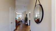This single-story residence is thoughtfully designed with a warm, neutral color palette and rich hardwood-style flooring that flows throughout the main living areas. A welcoming entryway corridor leads into the expansive open-concept living room, where soaring vaulted ceilings and a ceiling fan create an airy atmosphere. Large windows and a sliding glass door flood the space with natural light and provide access to an outdoor balcony, enhancing the sense of openness.

The kitchen is well-equipped with dark cabinetry, stainless steel appliances including a refrigerator, range, and microwave, and granite-style countertops that extend to a breakfast bar. Adjacent to the kitchen, the dining area accommodates a round table and benefits from generous natural light through a large window.

A dedicated office features a sizable work desk, natural light from a window with blinds, and enough space for additional seating, making it a functional workspace.

The primary bedroom offers plush carpet, multiple windows, and a ceiling fan, creating a restful retreat. Two bathrooms are present, each featuring dark vanity cabinetry, granite-style countertops, hardwood-style flooring, and a shower-tub combination. The overall ambiance is cohesive, modern, and comfortable throughout.