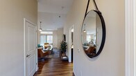 This single-story residence is thoughtfully designed with a warm, neutral color palette and rich hardwood-style flooring that flows throughout the main living areas. A welcoming entryway corridor leads into the expansive open-concept living room, where soaring vaulted ceilings and a ceiling fan create an airy atmosphere. Large windows and a sliding glass door flood the space with natural light and provide access to an outdoor balcony, enhancing the sense of openness.

The kitchen is well-equipped with dark cabinetry, stainless steel appliances including a refrigerator, range, and microwave, and granite-style countertops that extend to a breakfast bar. Adjacent to the kitchen, the dining area accommodates a round table and benefits from generous natural light through a large window.

A dedicated office features a sizable work desk, natural light from a window with blinds, and enough space for additional seating, making it a functional workspace.

The primary bedroom offers plush carpet, multiple windows, and a ceiling fan, creating a restful retreat. Two bathrooms are present, each featuring dark vanity cabinetry, granite-style countertops, hardwood-style flooring, and a shower-tub combination. The overall ambiance is cohesive, modern, and comfortable throughout.