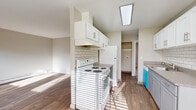 This single-floor, 3-bedroom, 1-bathroom residence offers a practical and well-appointed layout finished with a consistent neutral palette throughout. The living room is a bright, open space highlighted by sliding glass patio doors that invite natural light and provide direct access to an outdoor patio area, complemented by wood-look flooring and a baseboard heating system. The galley-style kitchen is efficiently designed with white upper cabinetry, gray lower cabinets, a subway tile backsplash, granite-style countertops, a stainless steel sink, and white appliances including a range and refrigerator. An overhead skylight-style fixture further brightens the kitchen. The three bedrooms feature plush carpet flooring; select rooms include ceiling fans, windows for natural light, and built-in closets with hanging rods. The shared full bathroom is cleanly finished with wood-look flooring, a gray vanity with granite-style countertops, a large mirror, and a shower-tub combination. A central hallway connects the rooms efficiently, and consistent neutral wall tones and modern hardware throughout lend the space a cohesive, move-in-ready feel.