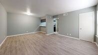 Located at 2302 Durwood St in Austin, TX, this single-floor, one-bedroom, one-bathroom residence offers a practical and well-appointed layout in the desirable 78704 zip code. The living room is the heart of the space, featuring light wood-look laminate flooring, soft sage-green walls, and a large window dressed with horizontal blinds that invite generous natural light. A built-in shelving unit adds functional storage along one wall, while a pass-through counter connects the living area to the kitchen, which is equipped with dark appliances and a countertop workspace. The bedroom is a comfortable retreat with plush wall-to-wall carpeting, a ceiling fan with integrated lighting, and a window overlooking outdoor greenery. A hallway connects the main living areas to a dedicated closet, providing ample storage. The bathroom features a full tub and shower combo with white tile surround, chrome fixtures, and wood-look flooring that ties the space together cohesively. Throughout the unit, consistent sage-green paint, crisp white trim, and clean finishes create a unified, calm aesthetic. The single-story layout ensures easy, step-free living throughout the entire space.