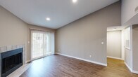 Located in Highland Heights, Kentucky, this three-bedroom, two-bathroom single-floor home offers a well-designed layout with a clean, modern aesthetic throughout. The open-concept living room is a welcoming centerpiece, featuring warm hardwood-style flooring, vaulted ceilings, a tile-surround fireplace, and a sliding glass door with vertical blinds that fills the space with natural light and provides outdoor access. The kitchen is efficiently laid out with white shaker cabinetry, quartz countertops, a single-basin undermount sink, and a full suite of stainless steel appliances including a refrigerator, range, microwave, and dishwasher. The primary bedroom offers a comfortable footprint, carpet flooring, a ceiling fan, a natural light window, and direct access to a walk-in closet with wire shelving. The additional bedrooms are carpeted and include windows that invite natural light. Both bathrooms are finished with quartz countertops, white cabinetry, wide vanity mirrors, and hardwood-style flooring. A dedicated utility room and hallway complete the floor plan. Neutral warm-gray tones carry throughout, lending the home a cohesive and move-in-ready feel.