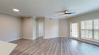 This 950-square-foot, single-story apartment in Cedar Park, TX offers 2 bedrooms and 2 bathrooms with a cohesive modern design throughout. Wood-look luxury vinyl plank flooring flows seamlessly across all living areas, complemented by neutral warm-gray walls and crisp white trim. The open kitchen and living area is anchored by a granite-topped island with an undermount sink and matte black faucet, paired with gray shaker cabinets, white quartz countertops, a subway tile backsplash, and stainless steel appliances. The living room features crown molding, a ceiling fan with light, and large windows with outdoor views that fill the space with natural light, plus access to an exterior door. The primary bedroom spans 180 square feet with a ceiling fan, a walk-in closet outfitted with wire shelving, and an en suite bathroom featuring a glass-enclosed walk-in shower with subway tile and matte black fixtures. The second bathroom includes a full soaking tub/shower combo with matching subway tile and a teal vanity. A dedicated laundry room houses a full-size washer and dryer. Two closets provide ample storage throughout the unit.