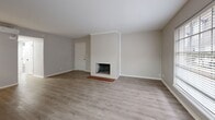This single-floor residence offers a well-organized layout with a clean, contemporary aesthetic throughout. The spacious living room serves as the heart of the home, anchored by a white-painted brick fireplace with a classic terra cotta tile hearth — a warm, character-rich focal point. Light-toned luxury vinyl plank flooring runs through the main living areas, complementing the neutral gray-toned walls and white trim for a cohesive, modern feel. Large windows allow natural light to flow freely through the living space, enhancing its open and airy atmosphere.

The galley-style kitchen is thoughtfully designed with two-tone cabinetry — white upper cabinets and gray lower cabinets — accented by matte black hardware. White quartz countertops, a classic subway tile backsplash, and a single-basin sink complete the look, while black appliances including a range, microwave, and refrigerator add a bold contrast. An adjacent dining area provides additional functional space.

The bedrooms feature plush carpeting and each offer two closets with paneled white doors fitted with matte black hardware, providing generous storage. The bathroom is finished with a gray vanity, white countertop, integrated sink, and a large mirror above, with consistent matte black fixtures throughout. A wall-mounted mini-split unit provides climate control in the bedroom areas.