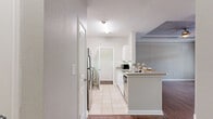 Located in Plano, TX, this well-designed one-bedroom, one-bathroom residence offers a thoughtful layout across a single floor, making efficient use of its compact footprint. The kitchen is a standout feature, showcasing white cabinetry, granite-style countertops, a stainless steel refrigerator, and a full suite of appliances including a range and dishwasher. Light tile flooring runs throughout the kitchen, which also benefits from a breakfast bar countertop — ideal for casual dining. A dedicated laundry area is conveniently accessible directly from the kitchen. The bedroom is a comfortable, carpeted retreat featuring warm neutral tones, a ceiling fan, and a window with blinds that invites natural light and views of the surrounding area. A dedicated closet provides ample storage. The bathroom is clean and functional, outfitted with tile flooring, a white vanity with ample drawer storage, a large mirror, and a toilet, all finished in a light, neutral palette. Throughout the residence, neutral wall tones and consistent finishes create a cohesive, move-in-ready aesthetic. Situated in the desirable Plano, TX area, this residence combines practical amenities with a clean, modern design.