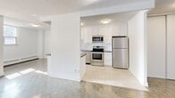 Located at 570 Birchmount Road in Toronto's Scarborough district, this 2-bedroom, 1-bathroom unit offers a practical and well-organized single-floor layout. The open-concept living, dining, and kitchen area forms the heart of the home, featuring polished floors that reflect natural light from large windows, and a textured ceiling that adds character. The kitchen is well-equipped with white shaker-style cabinetry, subway tile backsplash, stainless steel appliances including a refrigerator, range, and microwave, and a dark countertop peninsula that serves as a natural divider between the kitchen and living areas. Light tile flooring runs throughout the kitchen, contrasting with the parquet-style flooring found in the living and bedroom spaces. Both bedrooms are generously sized with clean white walls, parquet floors, baseboard heating, and windows that bring in natural light. The primary bedroom is notably spacious, offering ample room for furnishings. The bathroom features a clean, modern aesthetic with grey tile flooring, a white vanity with under-sink storage, a mirrored medicine cabinet, and a tiled tub surround. A hallway connects the main living areas to the bedrooms and bathroom, and a private balcony provides an outdoor retreat. The unit's bright, neutral palette creates a clean and welcoming atmosphere throughout.