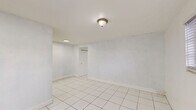Located at 7130 W 11th Ct in Hialeah, FL, this one-bedroom, one-bathroom apartment offers a practical and efficient single-floor layout. Light-colored ceramic tile flooring runs consistently throughout the unit, creating a clean, cohesive look. The bedroom is a comfortable size, featuring two windows with blinds that allow natural light to brighten the white walls, along with a closet for storage. The kitchen is laid out in a U-shape design, offering ample white cabinetry both above and below the counters. A striking green marble-style backsplash and countertop add a distinctive visual contrast against the white cabinets and tile floor. A window above the sink brings in natural light, and a full-size refrigerator is included. The bathroom carries a retro charm with mint green wall tiles surrounding the bathtub and shower combination, complemented by wood-toned cabinetry, a toilet, and a window for ventilation. Light wood-look flooring in the bathroom adds a warm touch. A hallway connects the rooms, providing a logical flow through the unit. The overall aesthetic is clean and straightforward, making it a practical space in a convenient Hialeah location.