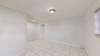 Located at 7130 W 11th Ct in Hialeah, FL, this one-bedroom, one-bathroom apartment offers a practical and efficient single-floor layout. Light-colored ceramic tile flooring runs consistently throughout the unit, creating a clean, cohesive look. The bedroom is a comfortable size, featuring two windows with blinds that allow natural light to brighten the white walls, along with a closet for storage. The kitchen is laid out in a U-shape design, offering ample white cabinetry both above and below the counters. A striking green marble-style backsplash and countertop add a distinctive visual contrast against the white cabinets and tile floor. A window above the sink brings in natural light, and a full-size refrigerator is included. The bathroom carries a retro charm with mint green wall tiles surrounding the bathtub and shower combination, complemented by wood-toned cabinetry, a toilet, and a window for ventilation. Light wood-look flooring in the bathroom adds a warm touch. A hallway connects the rooms, providing a logical flow through the unit. The overall aesthetic is clean and straightforward, making it a practical space in a convenient Hialeah location.