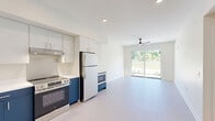 Located at 1470 Kalamazoo Ave SE in Grand Rapids, Michigan, this single-floor unit offers four bedrooms and two bathrooms within a thoughtfully arranged layout. The kitchen is a standout feature, showcasing bold navy blue lower cabinetry paired with crisp white upper cabinets, white quartz countertops, and a full suite of stainless steel appliances including a range, refrigerator, dishwasher, and microwave. The kitchen opens toward a living area equipped with a ceiling fan and a sliding glass door that invites natural light and outdoor views. The bedrooms are bright and calm, each featuring neutral carpet flooring, white walls, and windows overlooking greenery outside. The primary bedroom offers a comfortable sense of space with a ceiling fan and recessed lighting. Both bathrooms continue the navy and white design theme, featuring navy vanities with white countertops, modern fixtures, and well-lit mirrors. One bathroom includes a shower-tub combination, while the other serves as a half bath. Soft, light-toned flooring runs throughout the common areas, and clean white walls create a consistent, modern aesthetic across the entire unit. The overall ambiance is fresh, contemporary, and move-in ready.