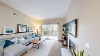 Located in the Rancho Bernardo community of San Diego, CA, this well-appointed two-bedroom, one-bathroom residence offers a thoughtfully designed single-level layout. The living room serves as a welcoming centerpiece, featuring vaulted ceilings, neutral tones, a cozy fireplace, and a sliding glass door that opens to a private balcony with views of lush greenery — filling the space with natural light and an airy atmosphere. A staircase-style shelving unit adds a modern, decorative touch to the living area.

The kitchen is functional and efficient, outfitted with warm wood cabinetry, granite-toned countertops, and white appliances including a range, microwave, and dishwasher. Adjacent to the kitchen, the dining room is brightened by multiple windows and offers a comfortable setting for everyday meals. An in-unit laundry area with a full-size washer and dryer adds everyday convenience, with additional natural light provided by a large window overlooking palm trees.

The generously sized primary bedroom features vaulted ceilings, plush carpeting, and direct access to a private outdoor space. The bathroom is equipped with a dual-sink vanity with ample cabinetry and a large mirror. The second bedroom is well-proportioned with soft carpeting and neutral walls. A connecting hallway ties all rooms together in a cohesive and practical floor plan.
