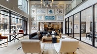 Located at 10720 Bell Tucker Lane in Louisville, Kentucky, this community clubhouse for The Louis Apartment Flats is a thoughtfully designed amenity space that blends modern sophistication with local Louisville character. The centerpiece is a soaring double-height lobby lounge, where an expansive gallery wall celebrates Louisville landmarks and culture through bold, custom signage and framed artwork. Plush seating arrangements, a leather sectional, and a statement chandelier create an inviting social atmosphere, while floor-to-ceiling black-framed glass walls and windows flood the space with natural light and offer views of the outdoor pool courtyard beyond.

Adjacent to the main lounge, a glass-enclosed conference and dining room provides a refined setting for private gatherings, featuring a large wooden table, designer pendant lighting, and motivational wall typography. The game lounge is a standout destination, outfitted with classic arcade machines, multiple wall-mounted flat-screen TVs, warm wood-plank flooring, a tray ceiling with shiplap detail, and direct access to the outdoor patio through full-height black-framed glass doors.

A fully equipped catering kitchen rounds out the space, featuring a large island with dark countertops, stainless steel appliances including a full-size French door refrigerator, light wood cabinetry, and industrial pendant lighting — ideal for hosting community events.