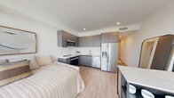 Located along Biscayne Boulevard in Miami's Edgewater neighborhood, this thoughtfully designed one-bedroom, one-bathroom unit maximizes every inch of its compact footprint with a smart open-plan layout and contemporary finishes throughout. Light wood-tone flooring runs seamlessly from the entrance through the main living area, complementing the crisp white walls and recessed lighting overhead.

The entry corridor features multiple closets offering generous storage, with louvered and panel doors adding subtle texture to the clean aesthetic. The main living space combines the bedroom, dining, and living areas in one cohesive room anchored by floor-to-ceiling windows that flood the interior with abundant natural light and frame expansive views of the Miami skyline. A private balcony extends the living space outdoors.

The kitchen is efficiently designed with dark wood-grain cabinetry extending to the ceiling, white countertops, and a full suite of stainless steel appliances including a refrigerator with ice maker, dishwasher, range, and over-the-range microwave. A peninsula provides casual seating and a natural division within the open layout.

The bathroom is finished in a clean, modern style with a dark wood vanity, white countertop, large mirror, and a glass-enclosed walk-in shower with subway tile surround. Every element of this unit reflects a cohesive modern design sensibility suited to Miami urban living.