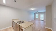 Located at 1547 Caprine Ct in Rock Hill, SC, this single-floor, one-bedroom, one-bathroom home offers a well-organized and efficient layout designed for comfortable everyday living. The open-concept kitchen and living area form the heart of the home, with light wood-look flooring flowing seamlessly throughout. The kitchen is equipped with stainless steel appliances — including a refrigerator, range, and over-the-range microwave — complemented by light wood cabinetry and a granite-style peninsula countertop with a double stainless steel sink, providing both prep space and a natural divide from the living area. The living room is bright and airy, featuring a ceiling fan with light fixture, a glass-panel exterior door, and a window that invites natural light and outdoor views. The generously sized bedroom offers ample space, with a ceiling fan, a natural light-filled window, and access to a closet. A connecting hallway leads to the full bathroom, which includes a tub-shower combination, a wood-vanity with granite-style countertop, and matching wood-look flooring. Neutral gray-toned walls throughout the home provide a clean, versatile backdrop, while white trim and paneled doors add a polished, cohesive finish to every room.