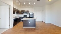 This well-appointed two-bedroom, two-bathroom residence in Denver, Colorado offers a thoughtfully designed single-floor layout that maximizes both functionality and comfort. The open-concept kitchen is a standout feature, boasting rich dark cabinetry, granite countertops, a central island, hardwood-style flooring, and a full suite of black stainless steel appliances including a gas range, built-in microwave, dishwasher, and refrigerator. Track lighting overhead adds a modern, polished touch to the space.

Both bedrooms are carpeted in a neutral tone, featuring bright windows with exterior views that allow natural light to fill each room. The primary bedroom offers a generous footprint with ample space. Four closets throughout the unit provide exceptional storage.

The two bathrooms are finished with warm stone-toned tile flooring and dark vanities topped with granite. The primary bath features a walk-in glass shower with accessibility grab bars, while the second bath includes a full tub-shower combination. Additional conveniences include an in-unit laundry area and a private balcony, rounding out this practical and stylish Denver home.