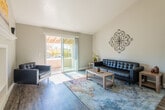 This single-floor residence offers a thoughtfully designed layout that balances comfort and functionality. The living area is a standout space, featuring vaulted ceilings that enhance the sense of openness, wood-style flooring, and a built-in shelving unit with a display mantle that serves as a natural focal point. A sliding glass door floods the room with natural light and provides direct access to a private balcony with tree-lined views, creating a seamless indoor-outdoor connection. Decorative wrought iron wall art adds an elegant, artistic touch to the living space.

The galley-style kitchen is efficiently designed with grey shaker cabinetry, quartz countertops, stainless steel appliances including a refrigerator, range, microwave, and dishwasher, complemented by a mosaic tile backsplash and light wood-style flooring.

The bedrooms feature plush carpeting, vaulted or angled ceilings, and windows that invite natural light. Each room offers a calm, neutral palette with ample space for furnishings. The bathroom is appointed with grey cabinetry, a white quartz vanity countertop, a glass-enclosed shower, and a private water closet, all finished with durable wood-look flooring. The overall ambiance throughout is clean, modern, and inviting.