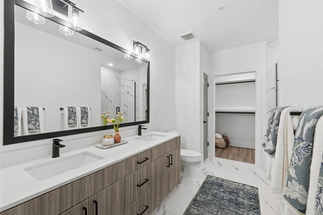 Baño con encimeras de cuarzo, lavabos dobles, ducha amplia y vestidor. - Linz Bayview