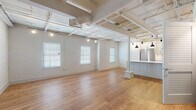 Located at 223 S Holly St in Columbia, SC's Rosewood neighborhood, this single-floor loft unit showcases a compelling blend of industrial character and modern finishes throughout. The expansive open-plan living area commands immediate attention with its soaring ceiling height, exposed structural trusses, and painted white brick walls that lend a raw yet refined aesthetic. Warm hardwood flooring extends throughout the main living space, complemented by track lighting that illuminates the room effectively.

The kitchen is well-appointed with light gray shaker-style cabinetry, white quartz countertops, a subtle tile backsplash, and a full suite of stainless steel appliances including a refrigerator, range, dishwasher, and microwave. A central island with panel detailing provides additional prep and seating space, while pendant lights overhead add a polished touch.

The bedroom features painted brick walls, hardwood flooring, exposed trusses, and a stylish sliding barn door that opens to an adjoining bathroom. The bathroom is finished with marble-style tile flooring, a walk-in shower with black-framed glass enclosure, and access to a dedicated walk-in closet. Additional rooms are accessible via French doors, offering flexible use of space throughout.