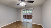 Located at 10121 Windmill Lakes Blvd in Houston, TX, this single-floor, one-bedroom, one-bathroom residence offers a well-organized layout designed for comfortable everyday living. The open-concept living, dining, and kitchen area serves as the heart of the home, featuring wood-look flooring throughout. The galley-style kitchen is outfitted with white cabinetry, a subway tile backsplash, black appliances including a refrigerator, range, microwave, and dishwasher, track lighting overhead, and a pantry for additional storage. A breakfast bar connects the kitchen to the dining and living area. The living room is bright and airy, with a ceiling fan and sliding glass doors that open onto a private balcony, offering outdoor views of surrounding greenery. The bedroom features plush carpet, a ceiling fan, a natural-light-filled window with blinds, and access to two closets for ample storage. The bathroom includes a full tub-shower combination with white tile surround. Neutral gray walls and consistent finishes throughout create a clean, cohesive aesthetic. The layout also benefits from thoughtful storage solutions, including two dedicated closet spaces, making this a highly functional and well-appointed residence.