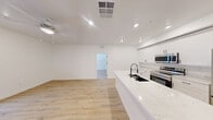 Located at 2555 N Rancho Dr in Las Vegas, NV, this well-appointed 2-bedroom, 2-bathroom residence offers a clean, modern aesthetic throughout its thoughtfully designed single-level floor plan. Light-toned luxury vinyl plank flooring runs continuously throughout the space, complementing the bright white walls and recessed lighting that create a fresh, airy atmosphere.

The open-concept kitchen and living area serves as the heart of the home. The kitchen is outfitted with full-height white shaker cabinetry, a striking quartz countertop island with an undermount sink and matte black fixtures, and a complete suite of stainless steel appliances including a range, over-the-range microwave, and refrigerator. A ceiling fan overhead adds comfort to the adjoining living area.

A bright hallway with transom windows above each doorway connects the bedrooms and bathrooms. The spacious primary bedroom features a ceiling fan, a sliding glass door opening to a private balcony, and a generous walk-in closet with multi-level shelving and hanging rods. The second bedroom includes a ceiling fan, a sliding door closet, and a large window that fills the room with natural light. Both bathrooms are finished with white vanities, matte black hardware, and matching flooring. A dedicated laundry room houses a full-size top-loading washer and dryer.