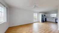 This well-appointed single-floor space offers a clean, modern aesthetic throughout. The open-concept living area is bathed in natural light from large multi-pane windows and features warm luxury vinyl plank flooring that extends seamlessly through each room. A ceiling fan overhead enhances comfort in the spacious main living area, which flows directly into the kitchen. The kitchen is thoughtfully designed with crisp white shaker-style cabinetry, a white subway tile backsplash, a stainless steel refrigerator, dishwasher, and range, as well as a window above the sink that brings in additional natural light. A dedicated entryway with a solid front door and adjacent window offers a welcoming transition into the home. The bedrooms continue the consistent flooring and bright white wall palette, each equipped with ceiling fans and windows that allow for ample daylight and outdoor views. The bathroom is finished with full-height neutral tile surrounds in the tub-shower combo, complemented by tile flooring, a white vanity with storage cabinetry, and a half-tiled accent wall. Throughout the space, clean lines, neutral tones, and quality finishes come together to create a bright, functional, and inviting environment.