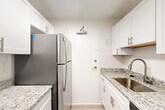 Located at 2000 N Adams St in Arlington, VA, this one-bedroom, one-bathroom unit offers a well-organized layout across a single floor, making efficient use of its space. The living room is bright and airy, finished with light wood-style luxury vinyl flooring and a large window that invites natural light and outdoor views of the surrounding neighborhood. The clean, neutral color palette throughout creates a cohesive and modern aesthetic.

The kitchen is thoughtfully designed in a galley configuration, featuring white shaker-style cabinetry with brushed nickel hardware, granite countertops, a stainless steel sink, and stainless steel appliances including a refrigerator and microwave. Light wood-style flooring continues seamlessly from the adjacent living area into the kitchen.

The bedroom is a comfortable and well-proportioned retreat, carpeted for warmth and fitted with a ceiling fan, a window with outdoor views, and generous closet space, including a set of bi-fold closet doors offering ample storage.

The bathroom is finished with white tile surrounding a full soaking tub and shower, complemented by a white vanity with granite countertops, brushed nickel fixtures, and a large mirror. A hallway connects the rooms, contributing to a functional and straightforward floor plan throughout this Arlington residence.