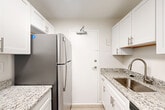 Located at 2000 N Adams St in Arlington, VA, this one-bedroom, one-bathroom unit offers a well-organized layout across a single floor, making efficient use of its space. The living room is bright and airy, finished with light wood-style luxury vinyl flooring and a large window that invites natural light and outdoor views of the surrounding neighborhood. The clean, neutral color palette throughout creates a cohesive and modern aesthetic.

The kitchen is thoughtfully designed in a galley configuration, featuring white shaker-style cabinetry with brushed nickel hardware, granite countertops, a stainless steel sink, and stainless steel appliances including a refrigerator and microwave. Light wood-style flooring continues seamlessly from the adjacent living area into the kitchen.

The bedroom is a comfortable and well-proportioned retreat, carpeted for warmth and fitted with a ceiling fan, a window with outdoor views, and generous closet space, including a set of bi-fold closet doors offering ample storage.

The bathroom is finished with white tile surrounding a full soaking tub and shower, complemented by a white vanity with granite countertops, brushed nickel fixtures, and a large mirror. A hallway connects the rooms, contributing to a functional and straightforward floor plan throughout this Arlington residence.