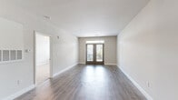 Located at 100 Comet Creek Lane in Goose Creek, South Carolina, this thoughtfully designed one-bedroom, one-bathroom residence offers a comfortable and modern living experience across a single floor. The open-concept living room serves as the heart of the home, featuring wood-look plank flooring, neutral toned walls, and a set of French doors topped with a transom window that floods the space with natural light and provides access to an outdoor balcony. The kitchen is well-equipped with gray shaker-style cabinetry, granite countertops, stainless steel appliances including a range and refrigerator, and track lighting overhead. A built-in desk nook with granite countertop and open wood shelving offers a functional workspace just off the kitchen. The bedroom is a generously sized retreat finished with plush carpet, a ceiling fan, and dual windows overlooking the surrounding greenery. A spacious walk-in closet with wire shelving provides ample storage. The bathroom features a granite-topped vanity with gray cabinetry, a large mirror, and a walk-in shower, all tied together with wood-look flooring. Clean lines and consistent finishes throughout create a cohesive, move-in-ready atmosphere.
