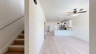This two-story home on Bost Drive in Fort Smith, Arkansas offers a thoughtfully designed layout spread across two floors. The main floor hosts an open-concept living room and kitchen combination, where light luxury vinyl plank flooring, neutral cream walls, and ceiling fans create a bright, cohesive atmosphere. The kitchen is well-appointed with white shaker cabinetry, granite countertops, stainless steel appliances including a French door refrigerator, electric range, and microwave, along with a peninsula island with a sink and pendant lighting overhead. A glass-panel back door allows additional natural light into the kitchen area.

The upper floor contains both bedrooms, two full bathrooms, and a dedicated laundry room. Each bedroom features light LVP flooring, ceiling fans, and windows that bring in natural light. The primary bedroom is a comfortable, well-proportioned space. The bathrooms are finished with white cabinetry, granite countertops, dual undermount sinks, round mirrors, and matte black hardware and fixtures. Three closets are distributed throughout the home, and a staircase connects the two levels, completing this efficiently planned residential space.