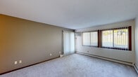 Located at 14319 Valley View Rd in Eden Prairie, Minnesota, this single-floor unit offers a straightforward, functional layout spread across several distinct spaces. The living area is generously proportioned, featuring soft carpeting, a textured ceiling, and a wall-mounted air conditioning unit. Large windows dressed with vertical blinds allow ample natural light to filter in, while a sliding glass door provides direct outdoor access and views of the surrounding greenery. Baseboard heaters run along the exterior walls, ensuring consistent warmth throughout.

The galley-style kitchen is efficiently arranged, featuring dark wood cabinetry, a double-basin sink with updated faucet, light-toned countertops, and tile-style flooring. White appliances, including a refrigerator, range, and dishwasher, are neatly integrated along the kitchen's length.

The bedrooms are carpeted and well-lit, each benefiting from windows with vertical blinds and baseboard heating. One bedroom includes a set of louvered bifold closet doors, offering organized storage. The overall layout, as seen in the 3D floor plan, includes a functional hallway connecting the kitchen, bedrooms, and living spaces, creating a cohesive and navigable interior throughout.