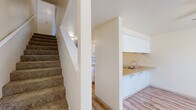 Located at 900 SE Centerpointe Dr in Corvallis, Oregon, this two-bedroom, two-bathroom residence spans two floors, offering a well-organized and practical layout. The main level features wood-look plank flooring throughout, providing a clean and cohesive aesthetic. The kitchen is designed with a peninsula-style breakfast bar, white cabinetry extending to the ceiling for ample storage, a countertop with an integrated sink, and white appliances including a range and refrigerator. A staircase connects the main level to the upper floor, where both bedrooms are located. Each bedroom is finished with plush carpeting and neutral wall tones, creating a comfortable and restful atmosphere. The generously sized primary bedroom offers a window with views of surrounding greenery, filling the room with natural light. The second bedroom similarly benefits from a large window and an adjacent closet with sliding panel doors. Both bathrooms feature wood-look flooring, with one full bathroom offering a tub-shower combination with chrome fixtures. The overall design is clean and straightforward, with a light, neutral color palette maintained throughout. The layout makes efficient use of space across both levels, offering comfortable living in a convenient Corvallis location.