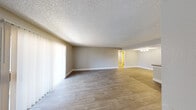 This single-floor unit offers a bright, well-maintained layout designed for comfortable everyday living. The expansive living area is finished with wood-look luxury vinyl plank flooring and neutral-toned walls, creating a calm, cohesive atmosphere throughout. A textured popcorn ceiling adds a classic touch, while vertical blinds along a generous window wall allow for flexible light control and privacy.

The kitchen is thoughtfully designed in a galley configuration, featuring white shaker-style cabinetry, dark countertops with a tile backsplash, and a full suite of stainless steel appliances including a refrigerator and electric range. A peninsula counter separates the kitchen from the main living space, providing an open, connected feel. A closeted pantry or storage area adds practical functionality.

The bedroom is a quiet, well-proportioned room with wood-look flooring, neutral walls, and a window fitted with horizontal blinds that allows natural light to fill the space.

The bathroom is clean and functional, featuring a white vanity with ample cabinet storage, a large mirror with overhead lighting, wood-look flooring, and a full tub-shower combination with a curved curtain rod. The overall aesthetic throughout the unit is modern, neutral, and move-in ready.