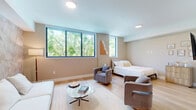 This 450 square foot apartment offers a thoughtful blend of comfort and functionality in a compact space. The single-floor layout comprises one bedroom and one bathroom, with the bedroom occupying a generous 390 square feet. The open-concept design creates a seamless flow between living areas, enhancing the sense of space.

The apartment features modern finishes throughout, with light wood flooring that adds warmth and continuity. Large windows in both the living area and bedroom flood the space with natural light, creating an airy ambiance and providing pleasant views of the surrounding greenery.

The kitchen, while compact, is well-equipped with stainless steel appliances and wooden cabinetry that complements the overall design. The living area accommodates a comfortable seating arrangement, including a sofa and stylish curved armchairs, centered around a sleek coffee table.

The bedroom, spacious at 390 square feet, offers ample room for a queen-sized bed and additional furnishings. The bathroom showcases a contemporary design with a glass-enclosed shower/tub combination, featuring sleek black hardware that contrasts beautifully with the white tiles.

Throughout the apartment, neutral tones dominate, creating a calming atmosphere. Subtle decorative elements, such as framed artwork and a statement wall in the living area, add character without overwhelming the space. This apartment efficiently utilizes every square foot, making it an ideal urban dwelling for those seeking a modern, low-maintenance lifestyle.